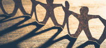 Ett band av pappersdockor som håller varandra i händerna